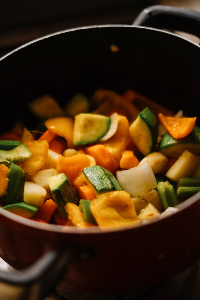Colorful chopped vegetables are being cooked in a pot. Perfect for healthy cooking concepts.